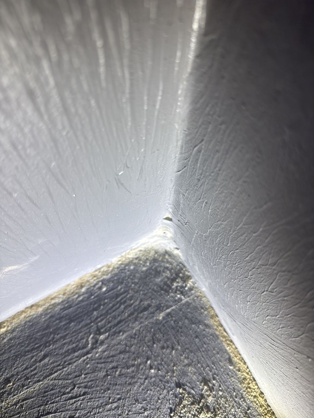 Thick build-up of membrane and bandage in a shower corner, uneven under tiles, found during a waterproofing inspection in Clyde North